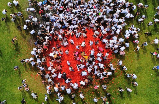 Aerial view of people participating in the tenth annual Tomato Fight Festival, known as “Tomatina”, in Sutamarchan, Boyaca Department, Colombia, on June 11, 2023. This year's festival is the first held since the lifting of the COVID-19 coronavirus pandemic restrictions. (Photo by Juan Barreto/AFP Photo)