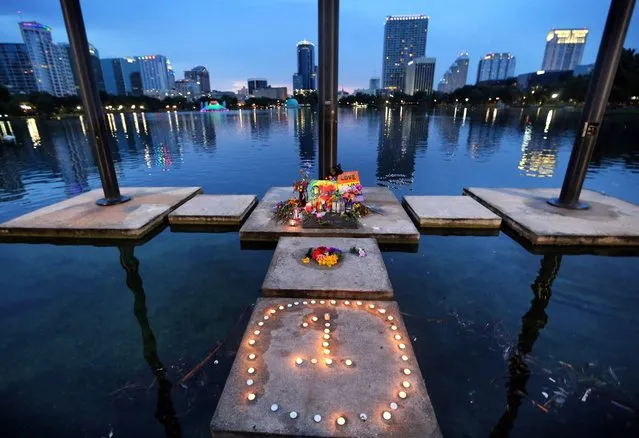 The symbol for “One Orlando” is spelled out at a makeshift memorial at Lake Eola in downtown Orlando, Fla., Saturday, June 18, 2016. Nearby, visitors lit candles and prayed at a larger memorial, at the Dr. Phillips Center for the Performing Arts, to mourn the victims of the Pulse massacre. (Photo by Joe Burbank/Orlando Sentinel via AP Photo)