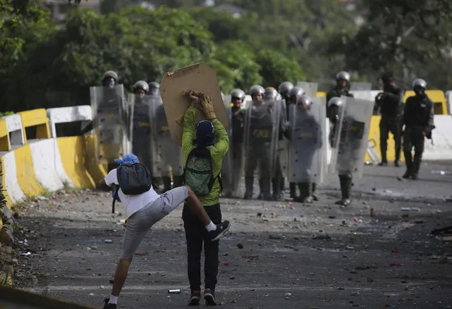 Anti-government protesters clash with security forces during a call by the opposition to block roads for 10 hours in Caracas, Venezuela, Monday, July 10, 2017. Opposition protests demanding new elections and decrying triple-digit inflation, food shortages and worsening crime continue as President Nicolas Maduro pushes forward with his plan to draft a new constitution (Photo by Fernando Llano/AP Photo)