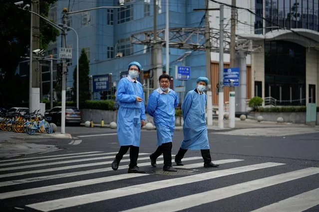 People in protective suits cross a street during lockdown, amid the coronavirus disease (COVID-19) pandemic, in Shanghai, China, May 26, 2022. (Photo by Aly Song/Reuters)
