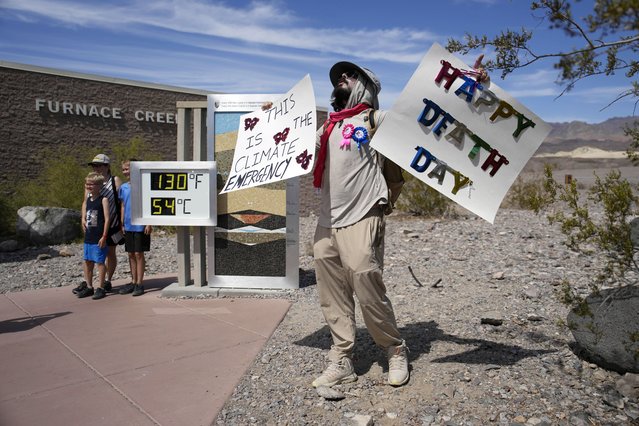 A demonstrator protests visitors to Death Valley National Park, Sunday, July 16, 2023, in Death Valley National Park, Calif. Death Valley's brutal temperatures come amid a blistering stretch of hot weather that has put roughly one-third of Americans under some type of heat advisory, watch or warning. The thermometer, at left, is not official but is a popular photo spot. (Phoot by John Locher/AP Photo)