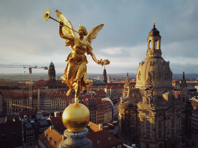 The golden sculpture of Pheme, the personification of fame and renown in Greek mythology, on the roof of the Dresden University of Visual Arts in Dresden, Germany on November 30, 2019, with the rebuilt Frauenkirche, which was destroyed in World War II bombing, in the background. (Photo by Amos Chapple/Radio Free Europe/Radio Liberty)