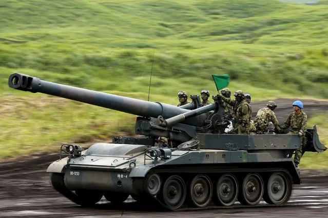 Japanese Ground Self-Defense Force soldiers ride on a 203mm self-propelled howitzer during an annual training session, which is based on a scenario to defend or retake islands in Japanese territory, near Mount Fuji at Higashifuji training field in Gotemba, west of Tokyo, August 18, 2015. (Photo by Yuya Shino/Reuters)