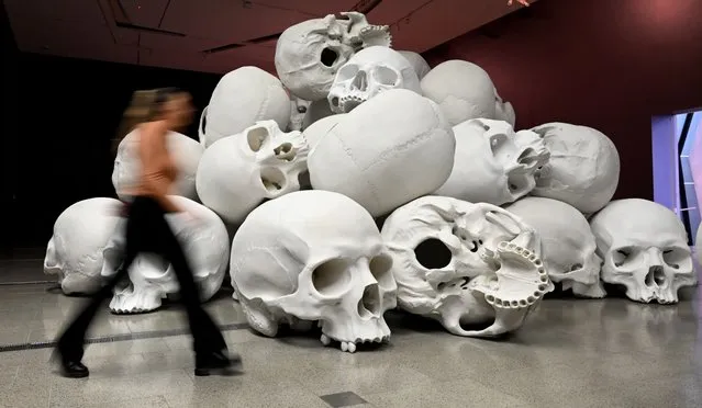 A person looks at Australian artist Ron Mueck's large-scale installation “Mass” which comprises more than 100 hand-cast skulls that collectively weigh approximately 5000 kilograms at an exhibition at the National Gallery of Victoria (NGV) in Melbourne on May 18, 2022. (Photo by William West/AFP Photo)