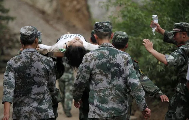 Paramilitary policemen carry an injured woman with a stretcher after an earthquake hit Ludian county of Zhaotong, Yunnan province August 3, 2014. The magnitude 6.5 earthquake struck southwestern China on Sunday, killing at least 175 people and leaving more than 180 missing and 1,400 injured in a remote area of Yunnan province, causing thousands of buildings, including a school, to collapse, Xinhua News Agency reported. (Photo by Reuters/China Daily)