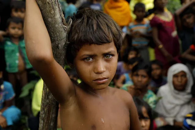 A Rohingya refugee girl looks next to newly arrived refugees who fled to Bangladesh from Myanmar in Ukhiya on September 6, 2017. More than 125,000 refugees have flooded across the border into Bangladesh. Most are Rohingya, a Muslim ethnic minority that the government of Buddhist- majority Myanmar largely does not recognise as citizens. (Photo by K.M. Asad/AFP Photo)
