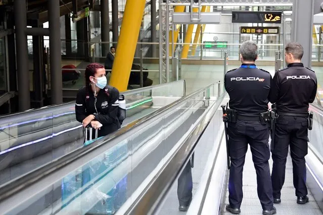 A passenger wearing a face mask as a protective measure looks at two police officers as they use a travelator at the Madrid-Barajas Adolfo Suarez Airport in Barajas on March 20, 2020. The coronavirus toll in Spain rose to 1,002 today following the deaths of 235 people in the past 24 hours, the health ministry said The number of cases also soared to 19,980, after another 2,833 infections were confirmed over the same period, the ministry's emergencies coordinator said. (Photo by Javier Soriano/AFP Photo)