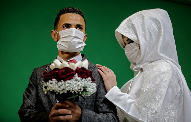 Palestinian groom Mohamed abu Daga and his bride Israa wear face masks amid the COVID-19 epidemic, during a photoshoot at a studio before their wedding ceremony in Khan Yunis in the southern Gaza Strip, on March 23, 2020. Authorities in Gaza confirmed on March 22 the first two cases of novel coronavirus, identifying them as Palestinians who had travelled to Pakistan and were being held in quarantine since their return, as the United Nations warned of potential disastrous outcomes to an outbreak given the high poverty rates and weak health system in the coastal strip, under Israeli blockade since 2007. (Photo by Said Khatib/AFP Photo)