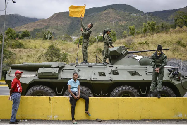 A woman sits next to an armored vehicle taking part in military exercises in Caracas, Venezuela, Saturday, February 15, 2020. (Photo by Matias Delacroix/AP Photo)