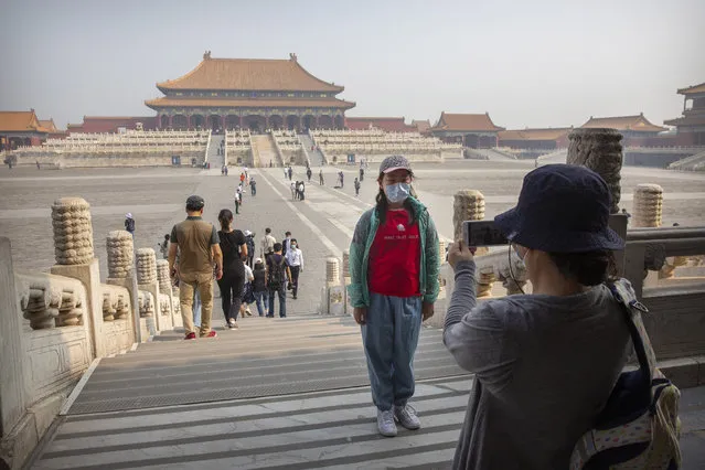 A visitor wearing a face mask to protect against the new coronavirus poses for a photo in the Forbidden City in Beijing, Friday, May 1, 2020. The Forbidden City reopened beginning on Friday, China's May Day holiday, to limited visitors after being closed to the public for more than three months during the coronavirus outbreak. (Photo by Mark Schiefelbein/AP Photo)