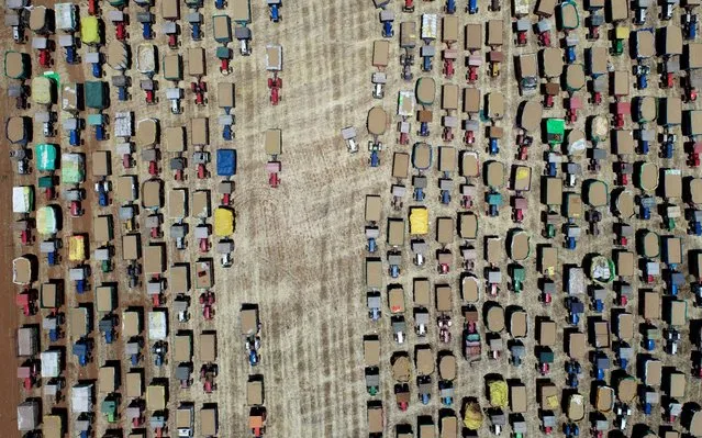 In this aerial photo taken on April 21, 2020, farmers line up their tractors carrying wheat grain at a wholesale market during a government-imposed nationwide lockdown as a preventive measure against the COVID-19 novel coronavirus, at Majholi Tehsil village, some 45 km from Jabalpur. (Photo by Uma Shankar Mishra/AFP Photo)