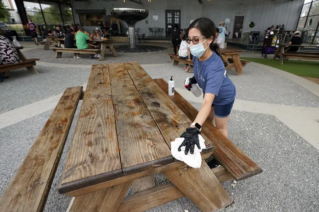 Hostess Carla Alexander disinfects a table at the Saint Arnold Brewing Company, Friday, June 26, 2020, in Houston. Texas Gov. Greg Abbott announced Friday that he is shutting bars back down and scaling back restaurant capacity to 50%, in response to the increasing number of COVID-19 cases in Texas. (Photo by David J. Phillip/AP Photo)