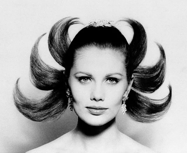 Six lacquered locks and a diamond brooch worn on top of the head give a Hindu-like effect to this hairdo created by Alexandre of Paris for the holiday season on December 2, 1964. The model is Maud Adams. (Photo by AP Photo)