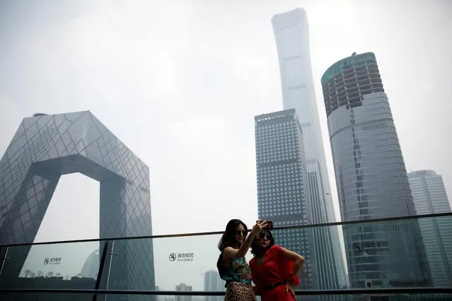 Women pose for pictures at a shopping mall near the CCTV headquarters and China Zun skyscraper in Beijing's central business district (CBD), China, July 16, 2020. (Photo by Tingshu Wang/Reuters)