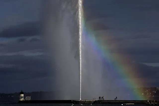 A rainbow is formed next to the water fountain (Jet d'eau) in front of a lighthouse in the harbor of Geneva, Switzerland, December 16, 2012. (Photo by Salvatore Di Nolfi/Keystone)