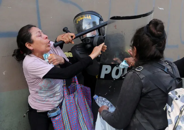 A woman struggles with a riot police officer during a protest demanding the dissolution of Congress and to hold democratic elections rather than recognise Dina Boluarte as Peru's President, after the ousting of Peruvian President Pedro Castillo, in Lima, Peru on December 12, 2022. (Photo by Sebastian Castaneda/Reuters)