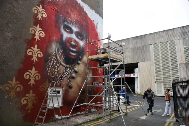 British street artist Dale Grimshaw (2nd R) creates an artwork for the “Sand Sea & Spray” Urban Art Festival in Blackpool, north west England on July 11, 2015. (Photo by Oli Scarff/AFP Photo)