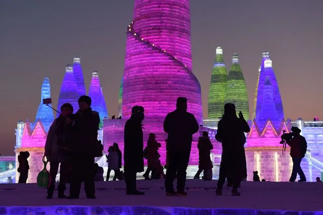 People visit the Harbin Ice and Snow World, part of the annual Harbin Ice and Snow Sculpture Festival in Harbin in China's northeast Heilongjiang province on January 4, 2018. The festival, which attracts hundreds of thousands of visitors annually, officially opens on January 5. (Photo by Greg Baker/AFP Photo)