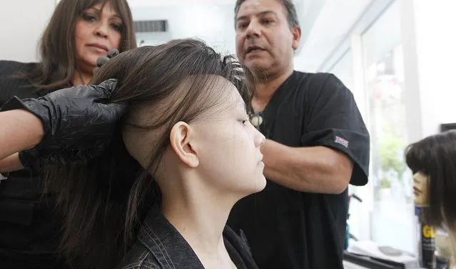 Hair stylist Marcelo Avatte (R) prepares to fit Isidora Serrano, a 14-year-old who lost her hair due to chemotherapy to treat her bone cancer, with a natural hair wig in the cancer ward of the Luis Calvo Mackenna Hospital in Santiago, October 23, 2014. (Photo by Rodrigo Garrido/Reuters)