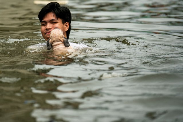 A man swims with his dog in a flooded street following heavy rains brought by Typhoon Co-may in Navotas City, Metro Manila, Philippines, on July 25, 2025. (Photo by Lisa Marie David/Reuters)