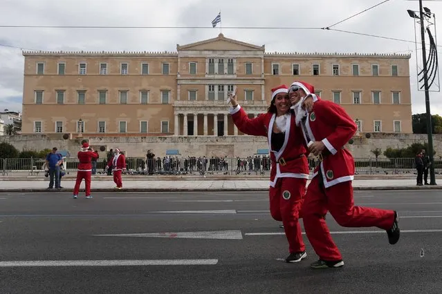 People dressed in Santa costumes run past the Greek parliament as they take part in the Santa Claus Run in Athens December 7, 2014. (Photo by Alkis Konstantinidis/Reuters)