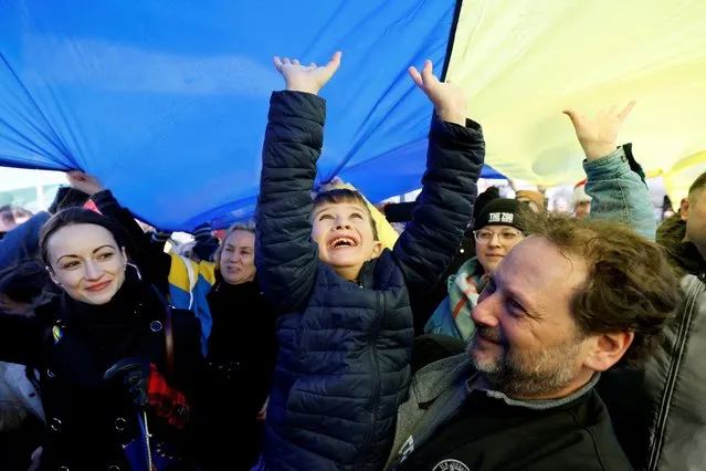 A child reacts under a giant Ukrainian flag as supporters of Ukraine take part in an event to mark the anniversary of Russia’s invasion of Ukraine in Ottawa, Ontario, Canada on February 20, 2023. (Photo by Blair Gable/Reuters)