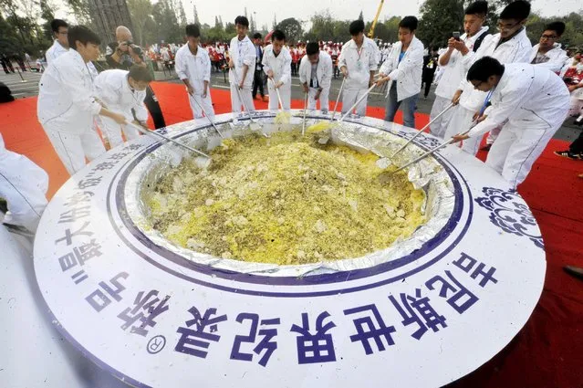 Participants stir a giant bowl of fried rice during a Guinness World Record attempt of the largest serving of fried rice, in Yangzhou, Jiangsu province, China, October 22, 2015. A total of 4,192 kilograms of fried rice was cooked in Yangzhou on Thursday as they successfully set the new Guinness World Record, local media reported. (Photo by Reuters/Stringer)