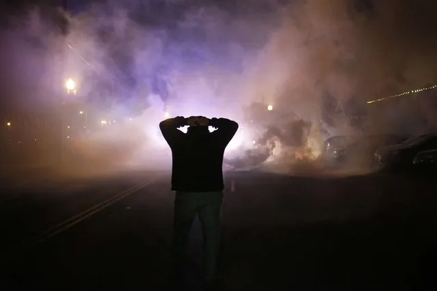 A protester stands with his hands on his head as a cloud of tear gas approaches after a grand jury returned no indictment in the shooting of Michael Brown in Ferguson, Missouri, in this November 24, 2014 file photo. (Photo by Adrees Latif/Reuters)