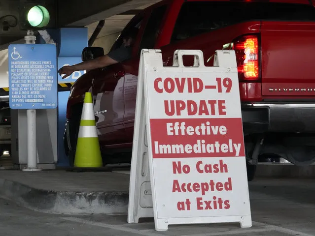 A sign posted reads “Covid-19 Update. Effective Inmediately. No Cash Accepted at Exits”, at a Los Angeles International Airport main parking lot in Los Angeles, Friday, November 13, 2020. California has become the second state to record 1 million confirmed coronavirus infections. The governors of California, Oregon and Washington issued travel advisories Friday, Nov. 13, 2020, urging people entering their states or returning from outside the states to self-quarantine to slow the spread of the coronavirus, California Gov. Gavin Newsom's office said. The advisories urge people to avoid non-essential out-of-state travel, ask people to self-quarantine for 14 days after arriving from another state or country and encourage residents to stay local, a statement said. (Photo by Damian Dovarganes/AP Photo)