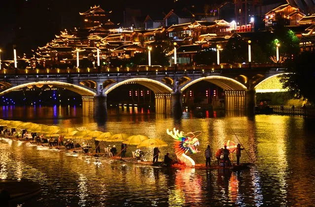 Tourists ride on bamboo rafts, which formed a dragon-shaped boat, on Gongshui river ahead of the Chinese New Year, the Year of the Rabbit, on January 16, 2023 in Xuan en County, Enshi Tujia and Miao Autonomous Prefecture, Hubei Province of China. (Photo by Wang Jun/VCG via Getty Images)