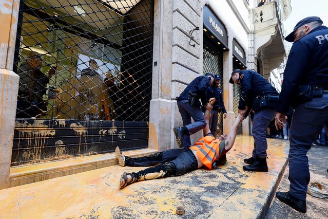 A Last Generation climate activist is dragged away by police officers after throwing washable paint on a Prada shop window in the city’s fashionable Via Condotti in Rome, Italy on May 16, 2024. (Photo by Cecilia Fabiano/AP Photo)