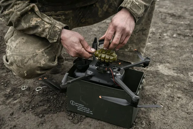 An Ukrainian serviceman attaches a hand grenade on a drone to use in an attack, near Bachmut, in the region of Donbas, on March 15, 2023. (Photo by Aris Messinis/AFP Photo)