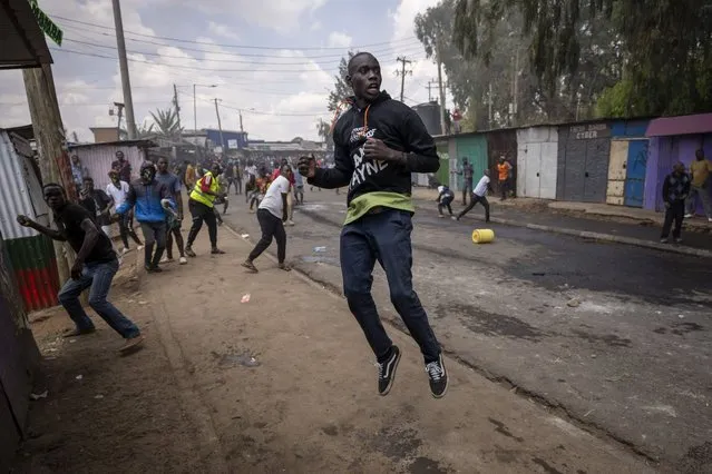 A protester jumps up to see where the rock he has thrown at police landed in the Kibera slum of Nairobi, Kenya Monday, March 20, 2023. (Photo by Ben Curtis/AP Photo)