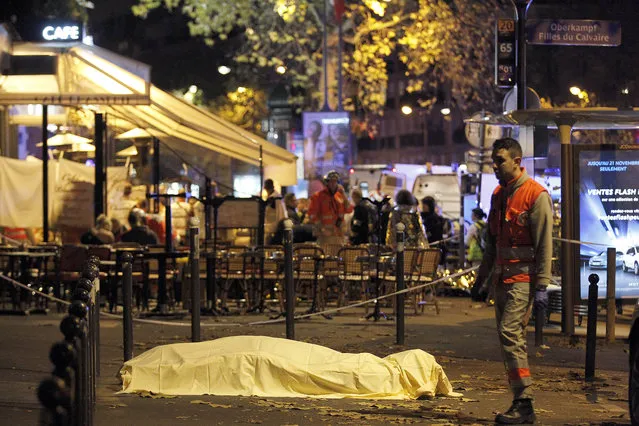 A victim's body lies covered on Boulevard des Filles du Calvaire, close to the Bataclan theater, early on November 14, 2015 in Paris, France. (Photo by Thierry Chesnot/Getty Images)