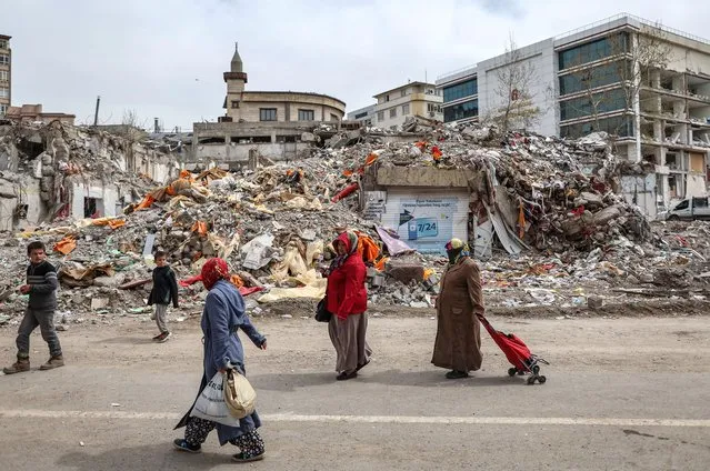 Women walks with shopping bags in front of collapsed buildings on the eve of Ramadan, in the aftermath of a powerful earthquake in Kahramanmaras, Turkey, 22 March 2023. More than 50,000 people died and thousands more were injured after major earthquakes struck southern Turkey and northern Syria on 06 February and again on 20 February 2023. (Photo by Erdem Sahin/EPA/EFE)