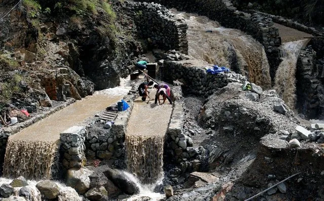 Local miners collect small rocks, as they mine for gold, from the waters that come from the mountains a day after Typhoon Haima struck Benguet province in northern Philippines, October 21, 2016. (Photo by Erik De Castro/Reuters)