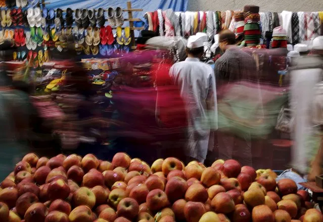 Shoppers crowd at a roadside market next to a handcart loaded with apples for sale in New Delhi, India, November 13, 2015. (Photo by Anindito Mukherjee/Reuters)