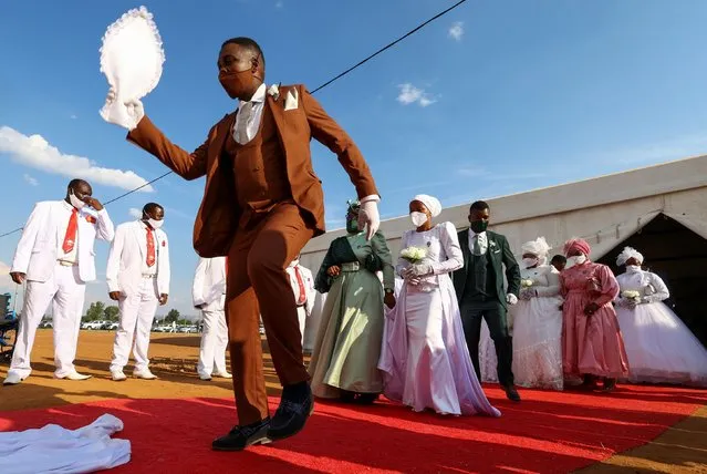 A groom dances as he is followed by some of the more than 800 couples taking part in the Easter Sunday mass wedding ceremony, organised by the International Pentecostal Holiness Church Jerusalem City (IPHC), in Kgabalatsane, in the North-West province, South Africa on April 9, 2023. (Photo by Siphiwe Sibeko/Reuters)