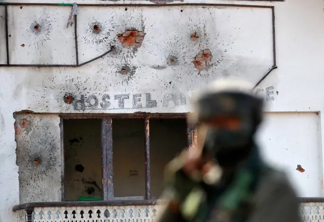 Bullet holes are seen on the wall of a house next to a soldier standing guard, after a gun battle between Indian army soldiers and suspected militants in Hokarsar, on the outskirts of Srinagar, December 30, 2020. (Photo by Danish Ismail/Reuters)