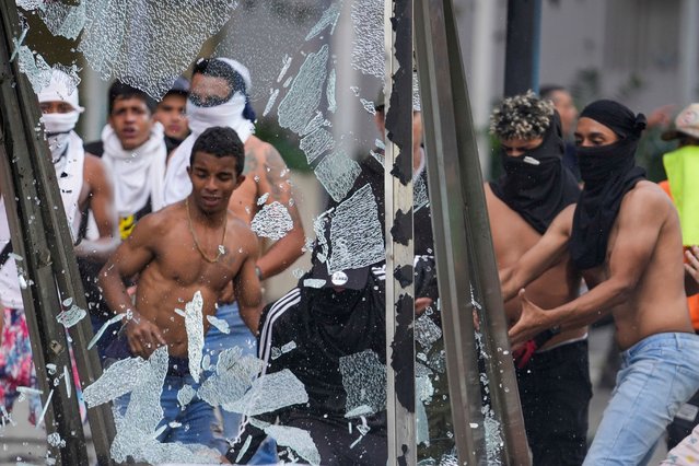 Protesters smash an advertising board during demonstrations against the official election results declaring President Nicolas Maduro's reelection, the day after the vote in Caracas, Venezuela, Monday, July 29, 2024. (Photo by Matias Delacroix/AP Photo)