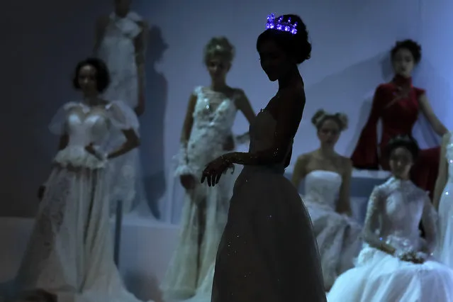 A model wears an illuminated crown as she presents a wedding dress designed by Tsai Meiyue on stage during the Mercedes-Benz China Fashion Week in Beijing, Thursday, October 27, 2016. (Photo by Andy Wong/AP Photo)