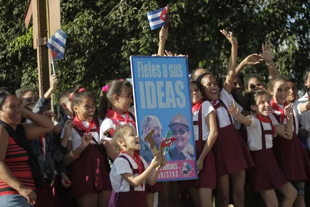 Children cheer and wave with a placard of Cuba's former President Fidel Castro (L) and his brother Cuba's President Raul Castro, as they watch a convoy of military trucks, re-enacting the triumphal 1959 march into Havana by Fidel and his “Barbudos” (bearded) guerrillas, driving past in Havana, January 8, 2015. (Photo by Reuters/Stringer)
