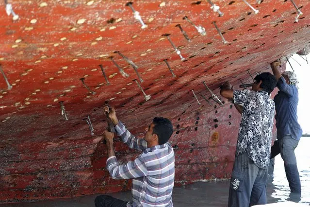 Workers restore a traditional wooden ship (lenj) in a shipyard on Iran's touristic Qeshm island in the Gulf, on April 29, 2023. (Photo by Atta Kenare/AFP Photo)