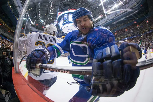 Vancouver Canucks' Matt Bartkowski, right, skates into the glass after a collision with Buffalo Sabres' Matt Moulson during the first period of an NHL hockey game in Vancouver, British Columbia on Monday December 7, 2015. (Photo by Darryl Dyck/The Canadian Press via AP Photo)