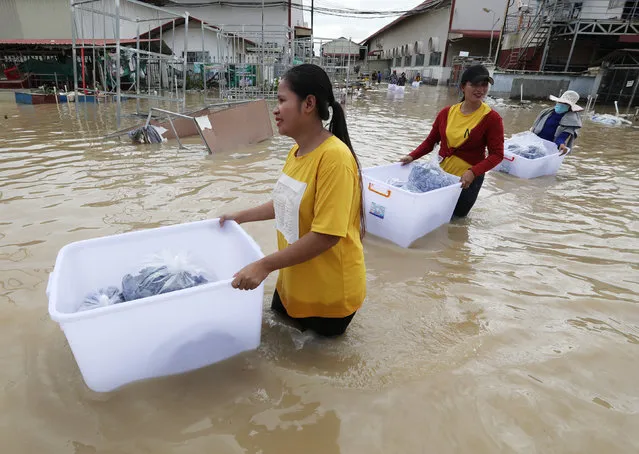 Garment workers gather clothes from a flooded factory on the outskirts of Phnom Penh, Cambodia, 19 October 2020. According to media reports, at least 22 people were killed and over 20,000 were evacuated in the aftermath of heavy floods. (Photo by Mak Remissa/EPA/EFE)