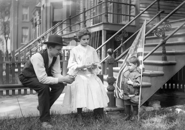 Family in Chicago celebrate 4th of July, circa 905. Mom and dad are possibly lighting firecrackers while their flag draped son waits in front of their Chicago walk up apartment in the early 20th century. (Photo by Kirn Vintage Stock/Corbis via Getty Images)