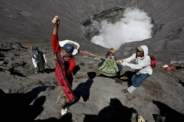 Villagers catch offerings thrown by Hindu worshippers at the crater of Mount Bromo during the Yadnya Kasada Festival on July 23, 2013 in Probolinggo, East Java, Indonesia. (Photo by Ulet Ifansasti/Getty Images)