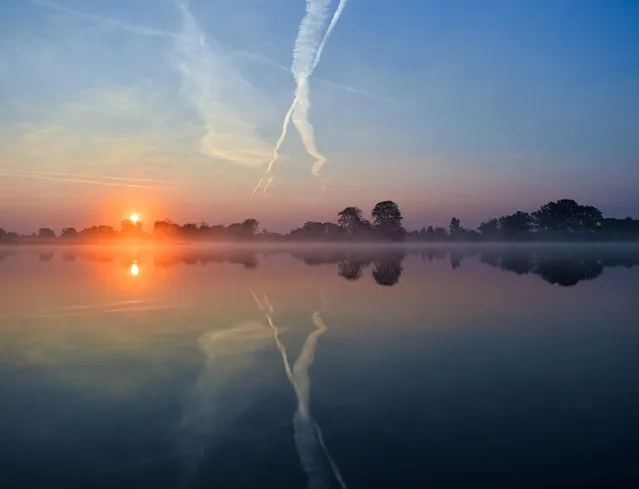 The rising sun's light is creating a spectrum of colors in the morning sky as it is reflected in the calm waters of the Oder river near Reitwein, Germany, on the border to Poland, early 09 September 2016. Meteorologist predict the weather to be mostly sunny with temperatures of up to 28 degrees Cesius in the region later the same day. (Photo by Patrick Pleul/EPA)