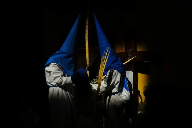 Hooded penitents from the “Entrada de Jesus en Jerusalen” brotherhood prepare to take part in a Holy Week Palm Sunday procession in Zaragoza, northern Spain, April 10, 2022. Hundreds of processions take place throughout Spain during the Easter Holy Week after two years due to the coronavirus pandemic. (Photo by Alvaro Barrientos/AP Photo)