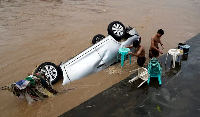 Residents wash chairs next to a submerged vehicle after flashfloods brought by continous monsoon rains in Marikina, Metro Manila, in Philippines on August 12, 2018. (Photo by Erik De Castro/Reuters)